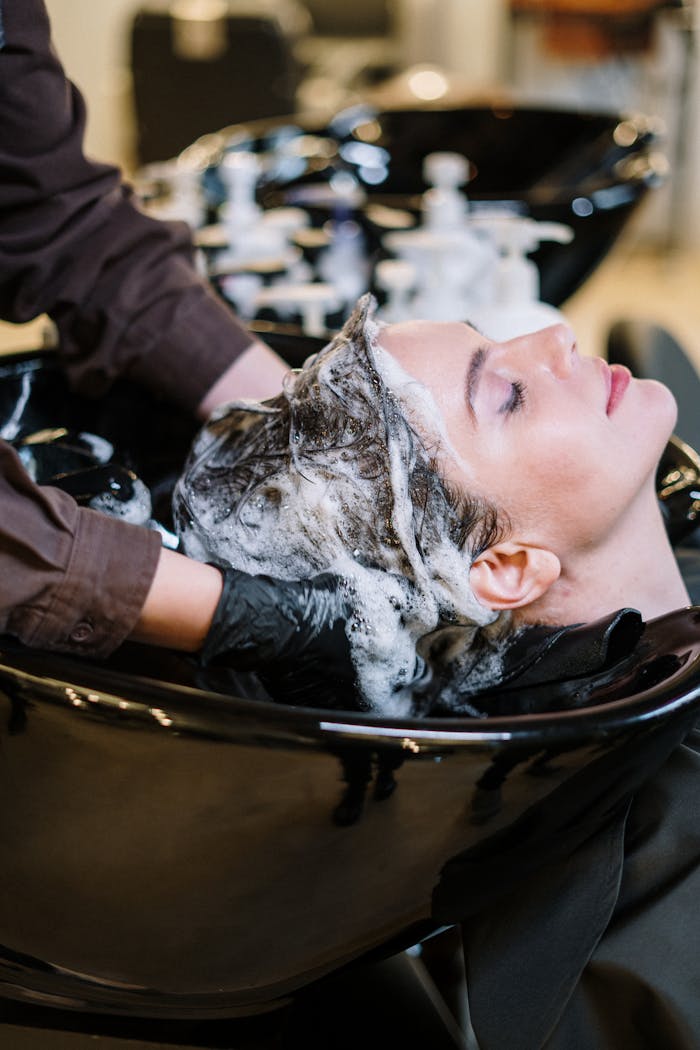 about-03 Professional hair stylist washing woman's hair in a modern salon setting.
